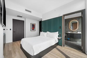 A modern bedroom with a bed, a bathroom with a glass door, and a painting on the wall. - Luxury E11EVEN Panoramic Bay & City View Suites (Miami)