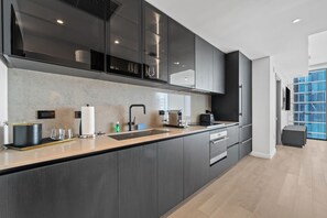 A modern kitchen with dark cabinetry, a stainless steel sink, and a built-in oven. - 22nd Floor E11EVEN Combined Suite Pool + City View (Miami)