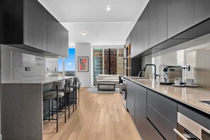A modern kitchen with a bar area, a dining table, and a view of the cityscape. - E11EVEN Executive Level Suite | Pool & City Views (Miami)
