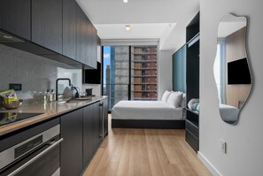 A modern bedroom with a bed, a bedside table, a mirror, and a view of a building through a window. - Luxury 49th Floor at E11EVEN w/ Rooftop Pool & Gym (Miami)