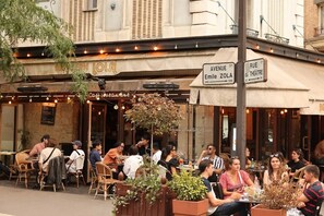 An outdoor cafe with tables and chairs, a sign for 'Cafe Restaurant,' and a street sign for 'Avenue Emile Zola.' - Luxury 150 m² Paris Duplex with Private Garden Terrace (Paris)