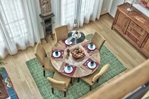 Mesa de jantar redonda com seis cadeiras, um vaso central e um armário de madeira ao fundo.