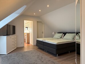 Een slaapkamer met een bed, een televisie op een dressoir, een inloopkast en een dakvenster.