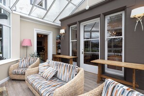 Um quarto aconchegante com uma janela grande, um sofá com almofadas listradas e uma mesa de madeira.