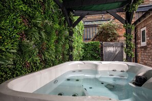 A hot tub surrounded by lush greenery and a brick wall. - The Clifton Townhouse, 5Bed with Hot Tub, King Bed (Scarborough)