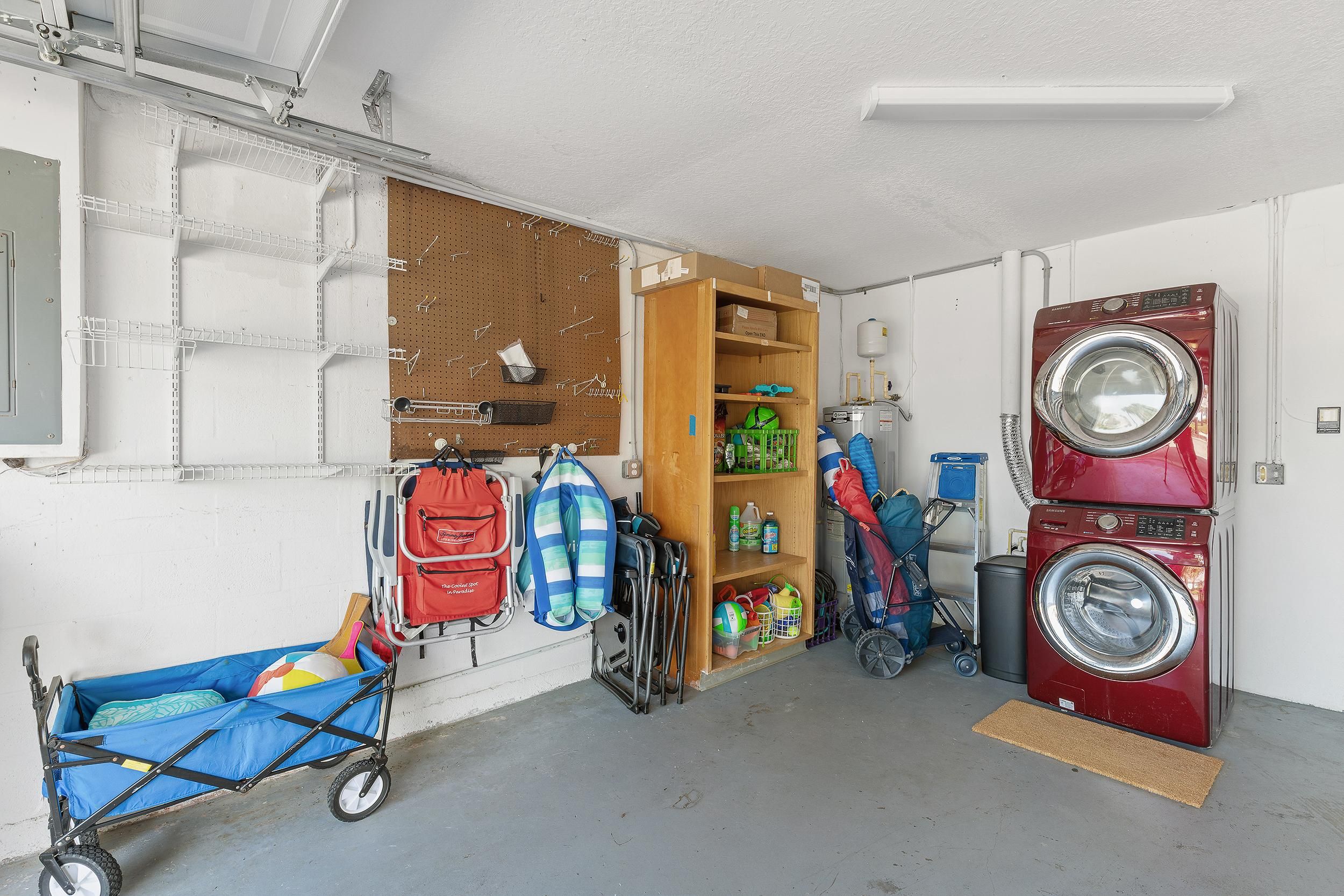 A laundry room with a red washing machine, a pegboard wall, and various storage items.