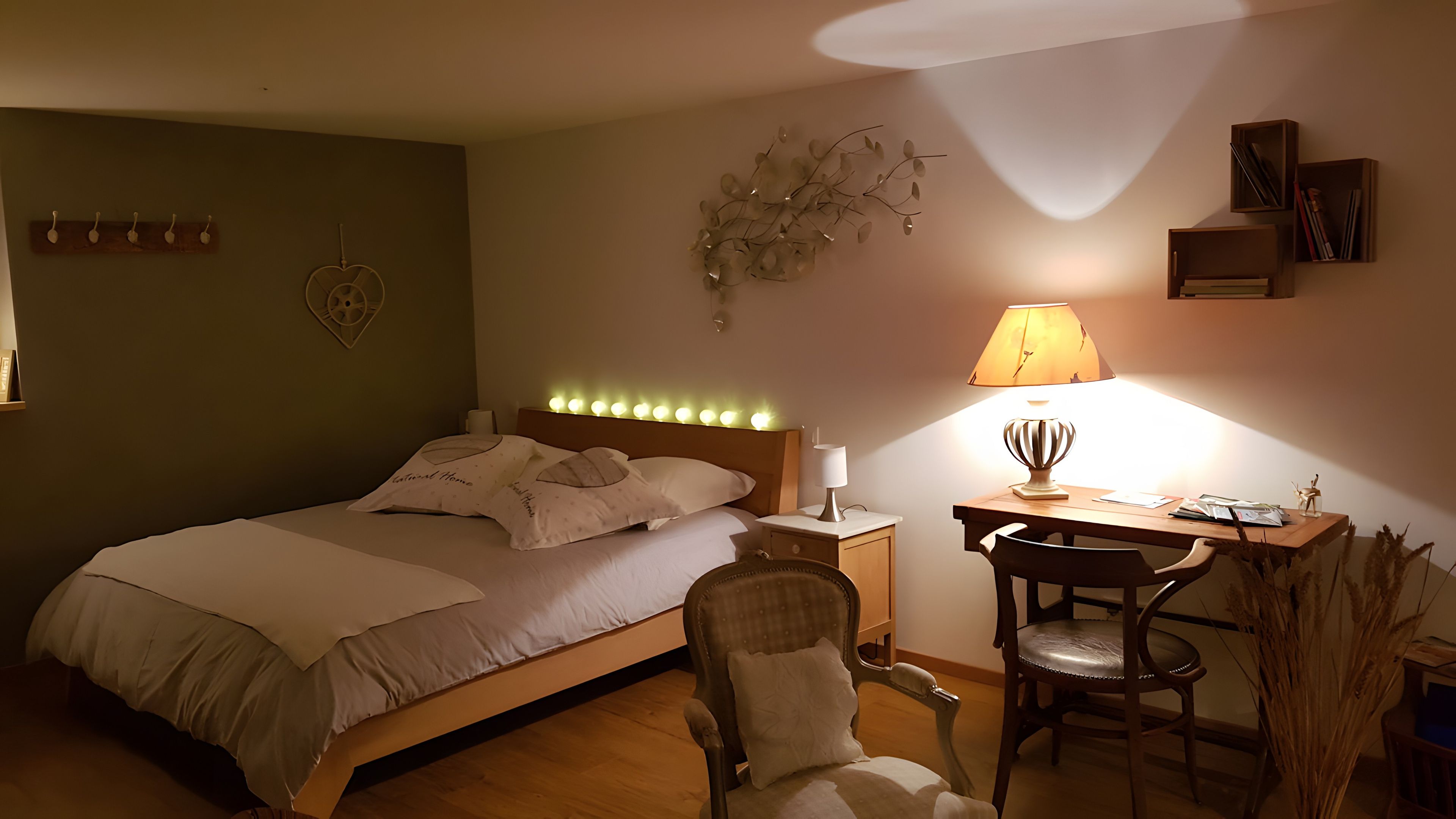 Ein Schlafzimmer mit Bett, Nachttisch, Lampe, Stuhl und Schreibtisch mit einer Lampe.
