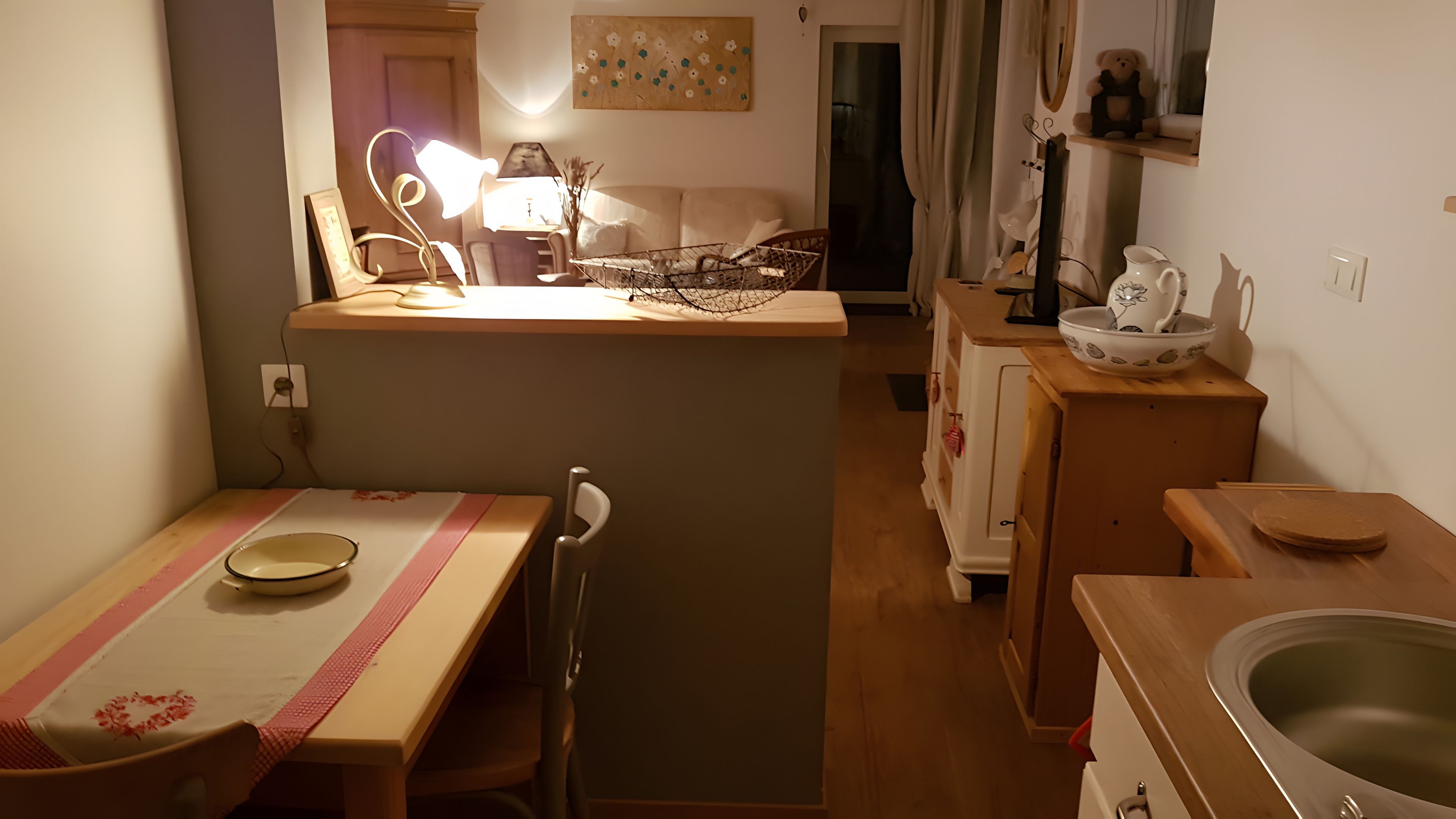 Eine kleine Küche mit Esstisch, Stühlen, Spüle und Kühlschrank.