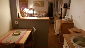 Eine kleine Küche mit Esstisch, Stühlen, Spüle und Kühlschrank.