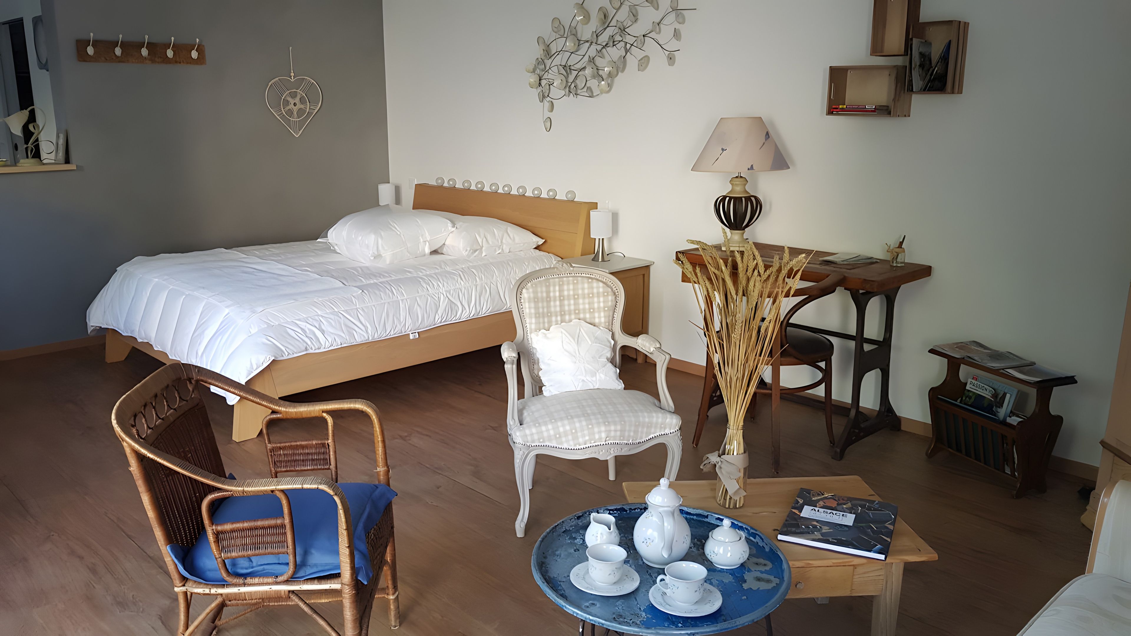 Un dormitorio con una cama, dos sillas, una mesa con una bandeja de objetos para té y una lámpara.