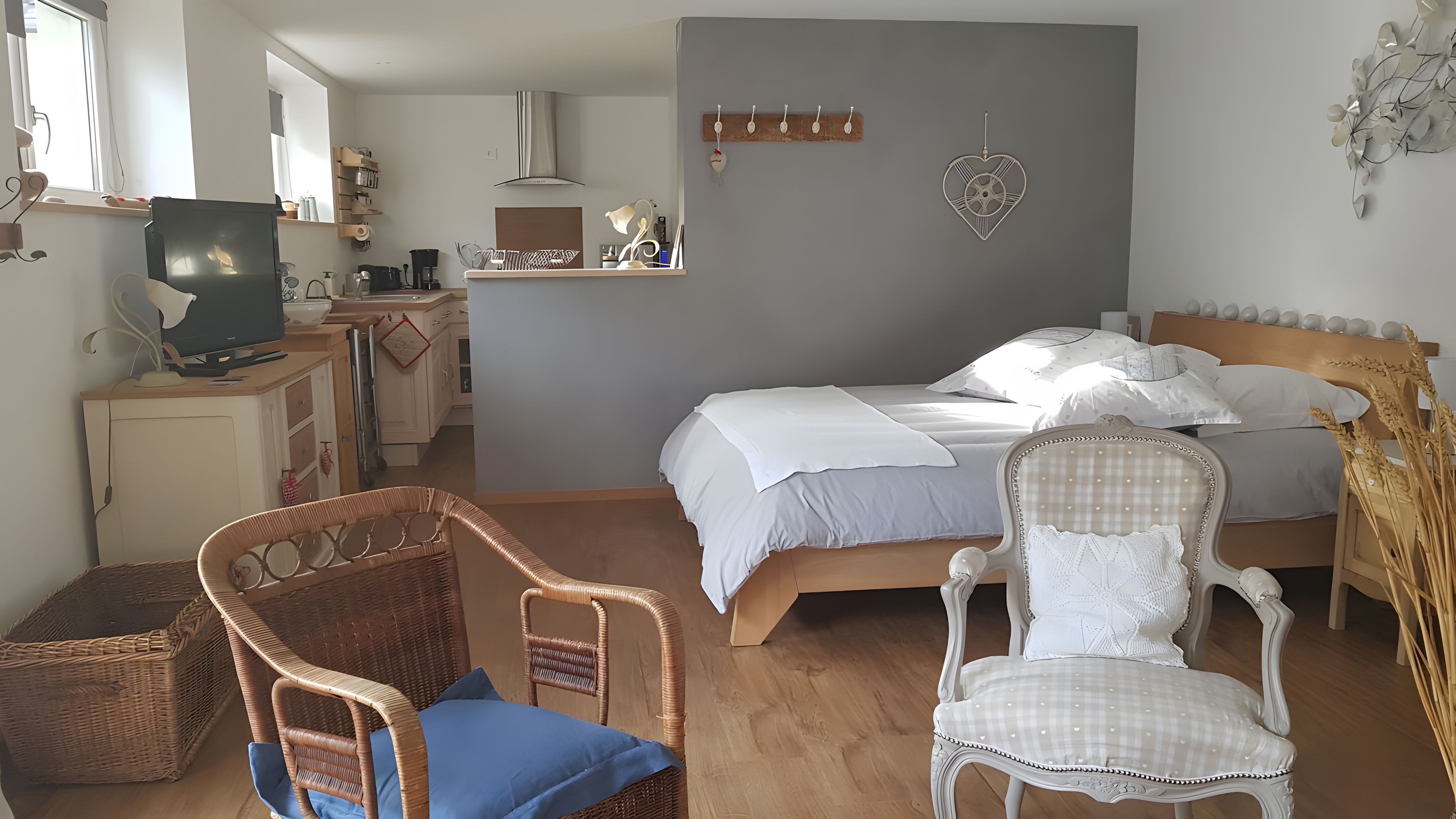 Ein Schlafzimmer mit einem Bett, zwei Stühlen, einem Fernseher und einer Küchenzeile.