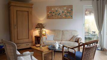 Ein Wohnzimmer mit Sofa, Schrank, Tisch mit Teeservice und einem Gemälde an der Wand.