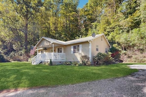 A two-story house with a porch, surrounded by trees and a well-maintained lawn. - Mountain House 2 Miles to WCU  Hot Tub Fire Pit & BBQ Fishing and Climbing Nearby (Cullowhee)
