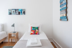 Ein Hotelzimmer mit einem Bett, einem Nachttisch mit Lampe, einem farbenfrohen Kissen und einer Wand mit mehreren Schildern.