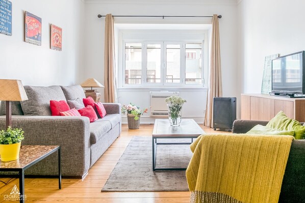 A living room with a sofa, a coffee table, a TV, and a window with curtains. - Casa da Avenida III Lisboa (Lisbon)