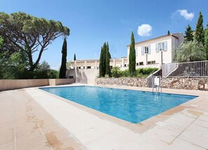 A rectangular swimming pool with a stone deck, surrounded by a low stone wall and a metal fence. - Les Bastides de Grimaud Apartment 407 in a quiet residence with a swimming pool. (Grimaud)