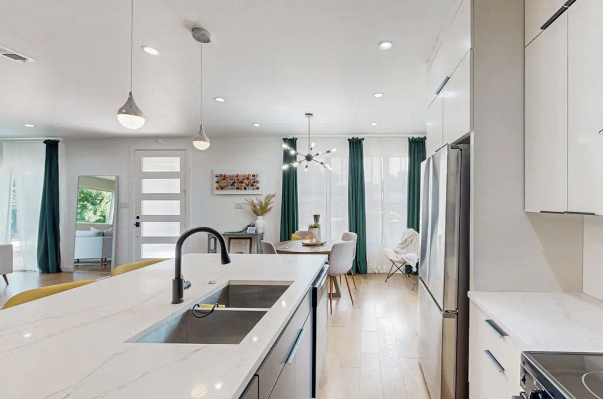 A modern kitchen with a central island, built-in appliances, and pendant lighting.