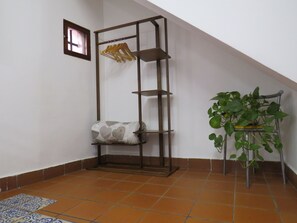 A corner room with a wooden shelf unit, a potted plant, and a patterned rug. - Quiet studio in the city center (Palermo)