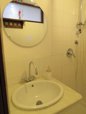 A bathroom with a sink, a mirror, a shower, and a soap dispenser. - Quiet studio in the city center (Palermo)