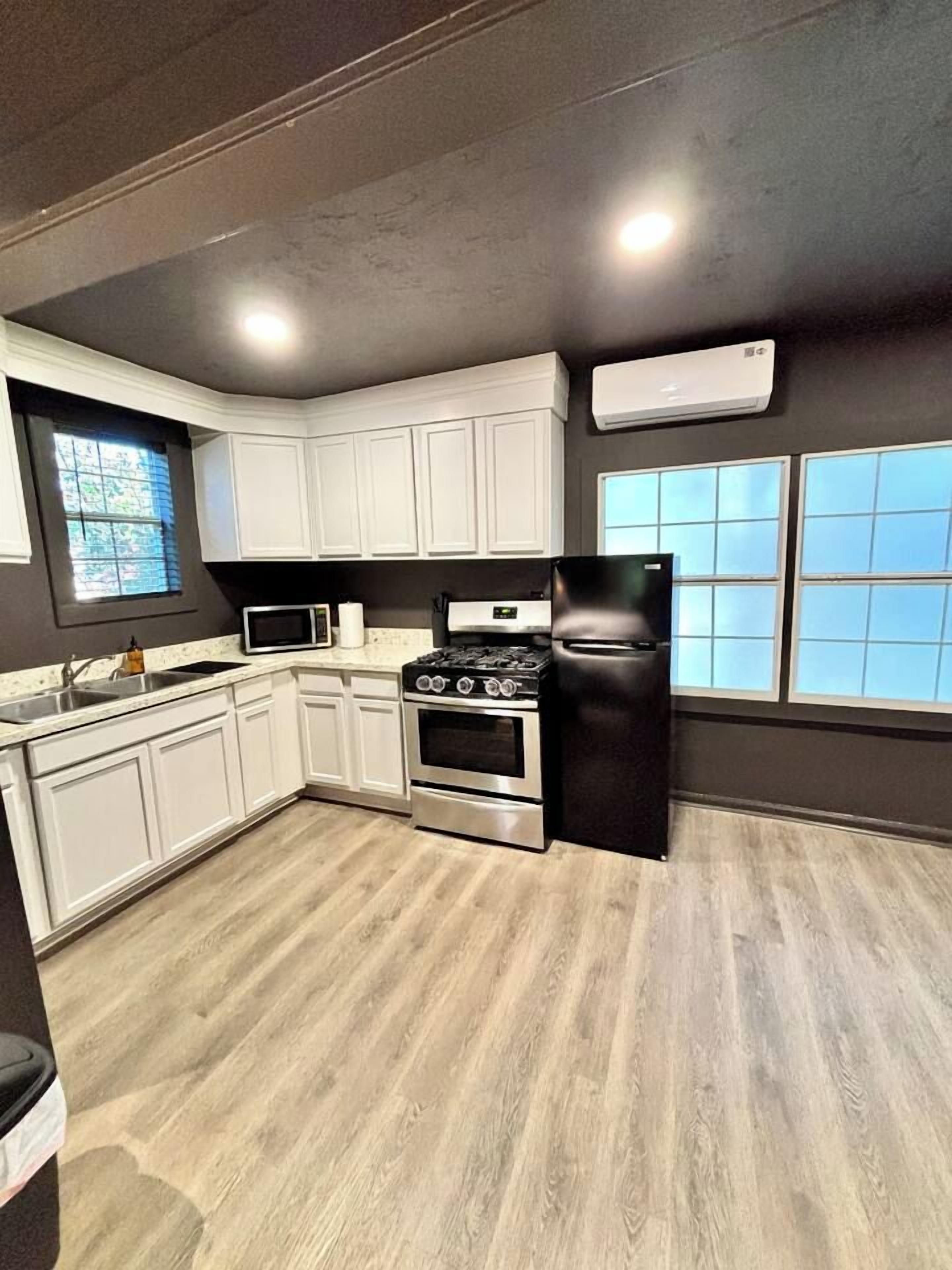 A kitchen with white cabinets, a black stove, and a black refrigerator.