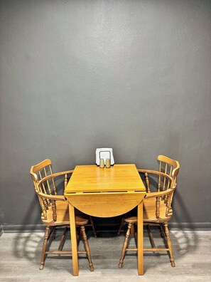 Una mesa de comedor con cuatro sillas de madera frente a una pared gris.