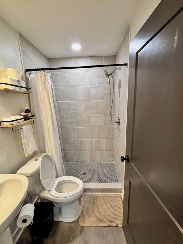 A bathroom with a shower, toilet, and sink.