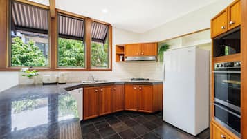 Eine Küche mit dunklen Fliesen, Holzschränken, einem weißen Kühlschrank und einem eingebauten Backofen.