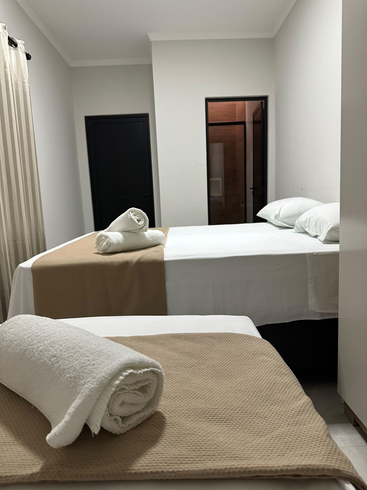 Habitación de hotel con dos camas, una puerta y una toalla en el suelo.