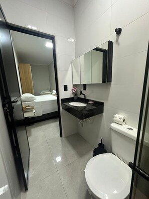 A modern bathroom with a white toilet, a black sink, and a mirror above it. - House Village A (Foz do Iguaçu)