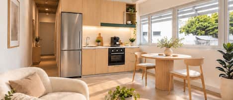 A modern kitchen with wooden cabinets, a stainless steel refrigerator, and a dining area with a round table and chairs.