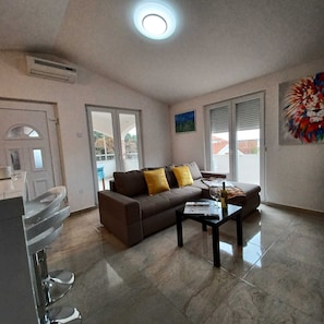 A living room with a sofa, coffee table, and a painting on the wall. - Beachfront Apartment With Balcony and Sea View (Vrsi)