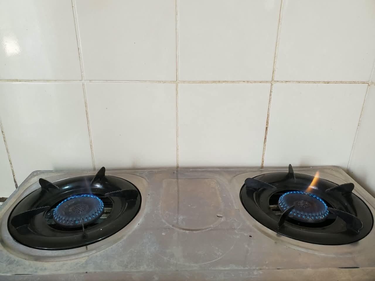 Cozinha com duas bocas de fogão a gás e painel de azulejos.
