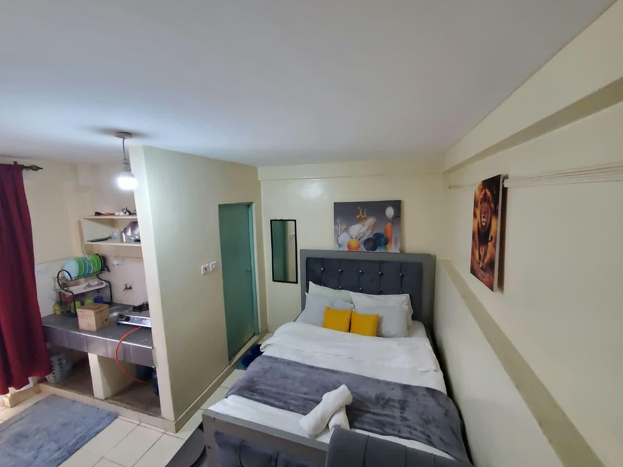 Quarto com cama, mesa de cabeceira, espelho e porta.