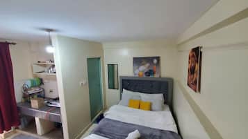 Quarto com cama, mesa de cabeceira, espelho e porta.