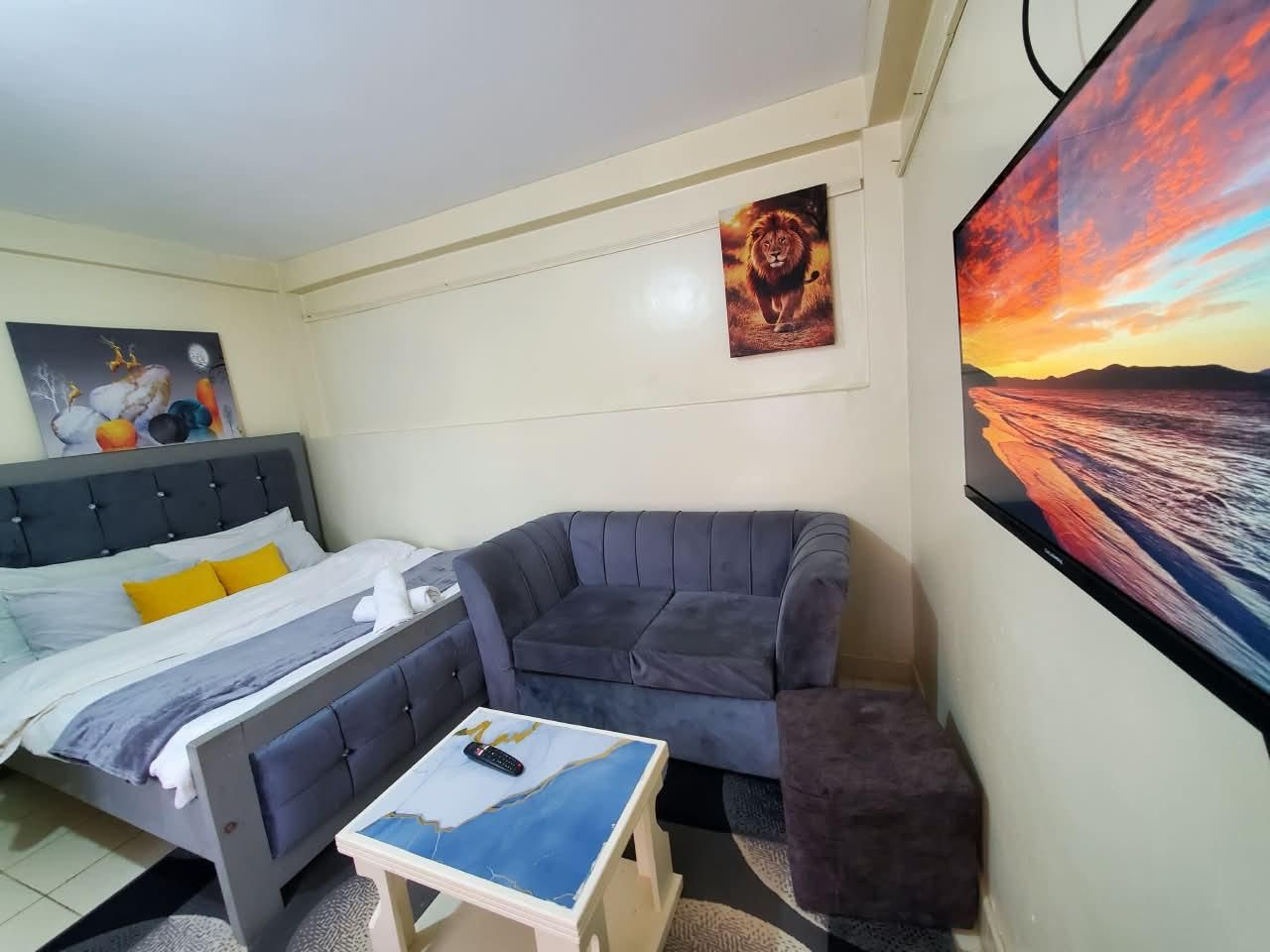 Quarto com cama, sofá, mesa pequena e televisão.