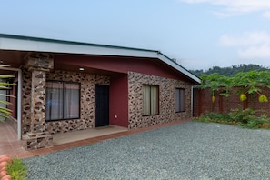 A house with a stone facade, a red door, and a gravel driveway. - Sun & Sea Twins Casa Sol (Savegre)