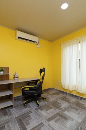 A room with a yellow wall, a desk with a chair, an air conditioner, a window with curtains, and a tiled floor. - Sun & Sea Twins Casa Sol (Savegre)