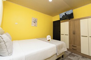 A room with a bed, a wardrobe, a painting, and a television on the wall. - Sun & Sea Twins Casa Sol (Savegre)