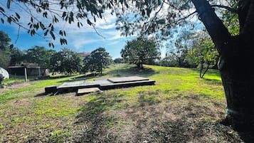 Un espacio al aire libre con una plataforma de madera, césped y árboles.