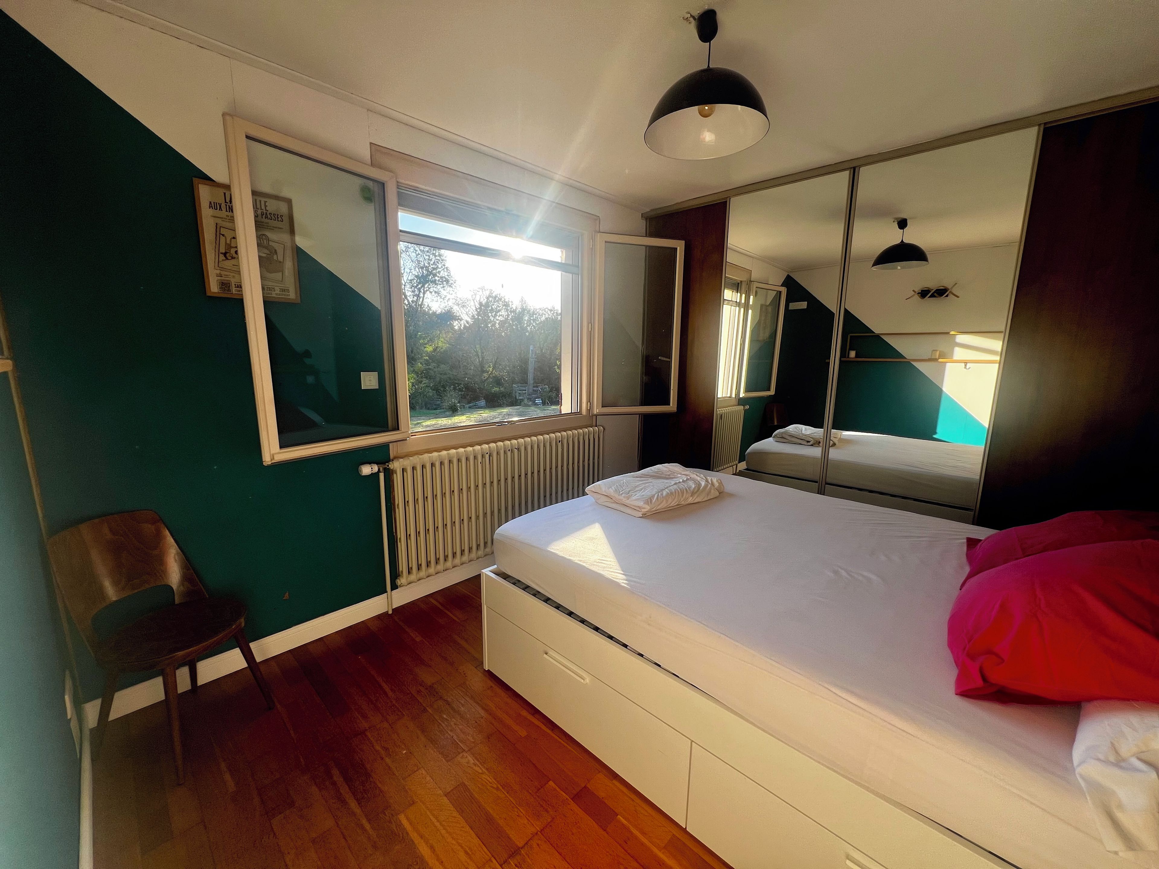 Une chambre à coucher avec un lit, une chaise, une fenêtre et un radiateur.