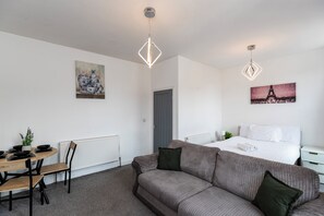 Ein modernes Hotelzimmer mit einem Bett, einer Couch, einem Essbereich mit Tisch und Stühlen sowie Kunstwerken an den Wänden.