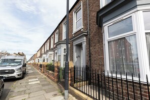Une rangée de maisons mitoyennes avec un trottoir pavé et un fourgon stationné.