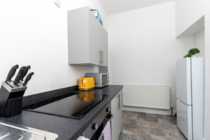 A compact kitchen with a black countertop, a yellow toaster, a white refrigerator, and a white cabinet. - Cape House- Cozy 1-bedroom studio, 4mins from Sunderland City Center (Sunderland)