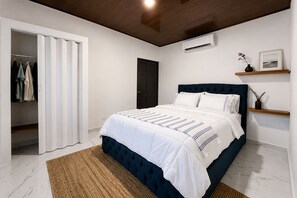 A bedroom with a bed, a wardrobe, a door, an air conditioning unit, and a shelf with a vase and picture. - Fantastic 3-bedroom house with AC in Provincia de Alajuela (Provincia de Alajuela)