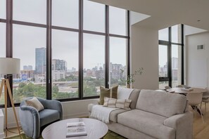 A modern living room with large windows, a sofa, a coffee table, and a floor lamp. - Luxury Designer Collection 419 - Fulton Market (Chicago)