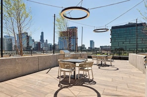 An outdoor patio with a table and chairs, a grill, and a view of a city skyline. - Luxury Designer Collection 519 - Fulton Market (Chicago)