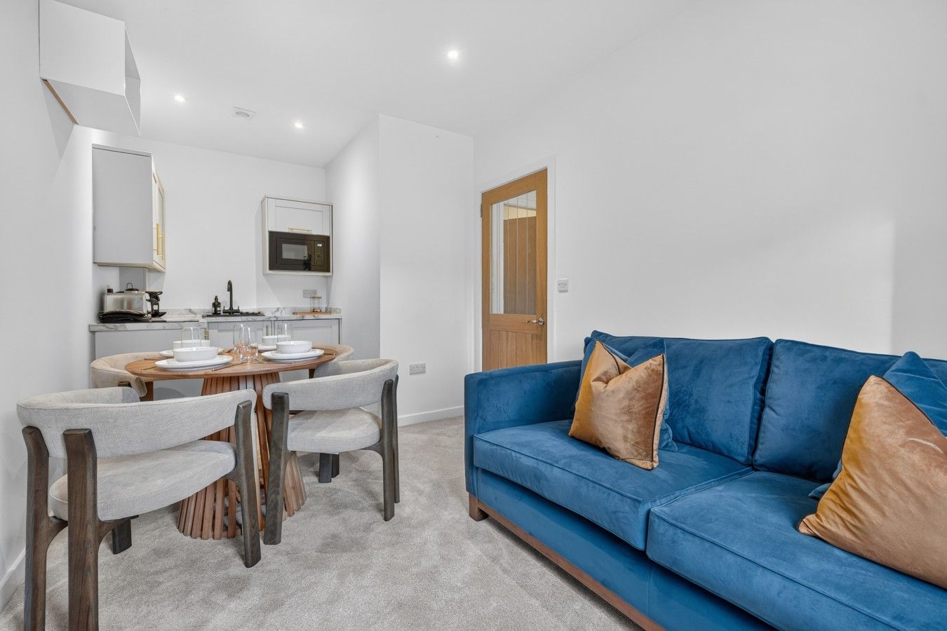 Ein modernes Wohnzimmer mit einem blauen Sofa und einem Essbereich mit rundem Tisch und Stühlen.