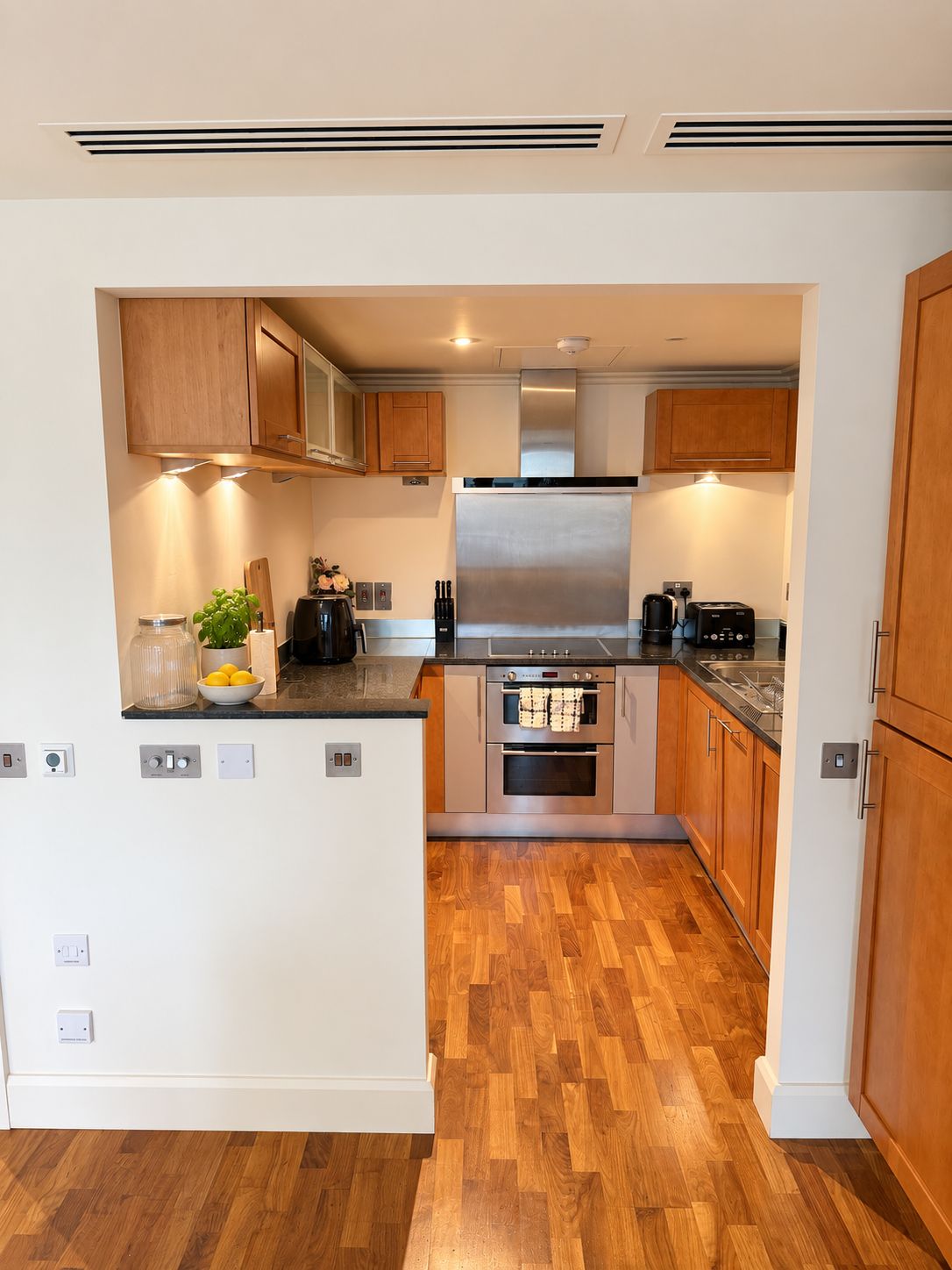 Una cocina moderna con armarios de madera, una campana extractora de acero inoxidable y un horno empotrado.