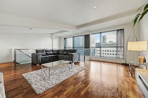Uma sala de estar moderna com um sofá modular, uma mesa de centro de vidro e uma janela ampla com vista para a cidade.