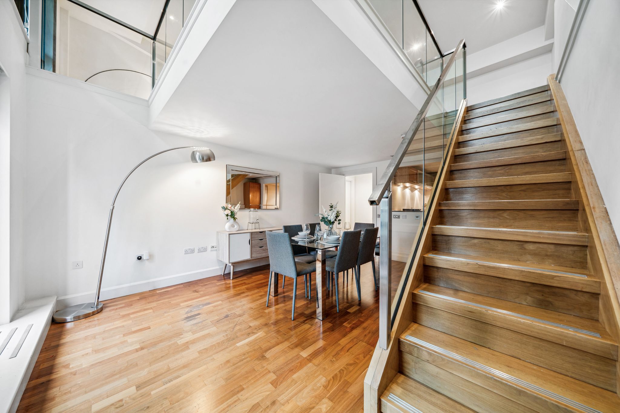 Un interior moderno con comedor, escalera y cocina.
